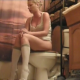 A blonde girl sits on a toilet and has some wet farts and some diarrhea. When finished, she gets up, cleans her has with her hands after wetting them in the sink, and towel dries her ass.